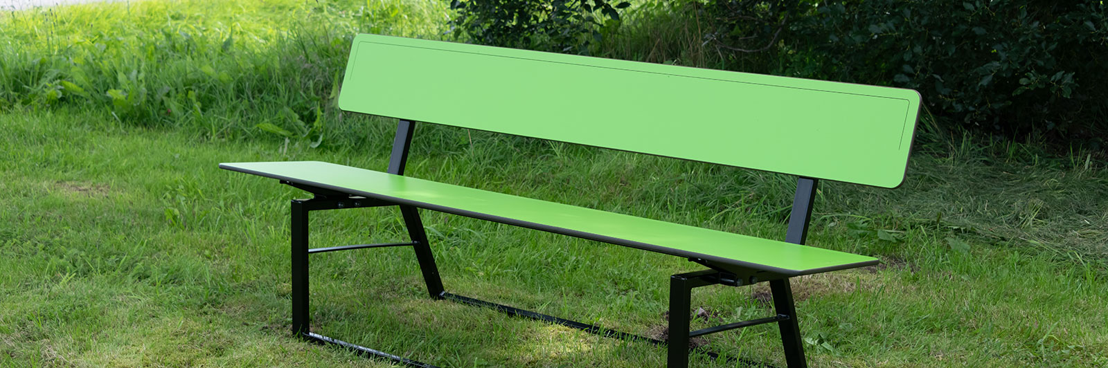 A green HPL park bench with backrest in a park.